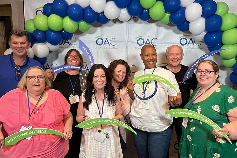 Group of OAC members smiling in front of blue and green balloon arch